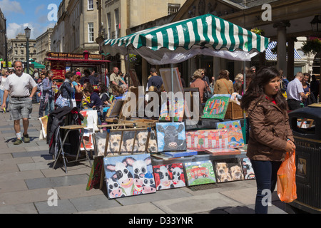 An artists stall selling apparently original paintings adjacent to the Roman Baths on Stall Street in Bath. Stock Photo