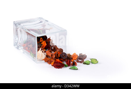 Fragrant natural potpourri with dried flowers, leaves and spices spilling out of a rectangular glass container onto a white background for that special fragrance in the house. Stock Photo