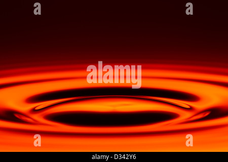 A close-up abstract image showing concentric ripples in a glossy, liquid-like surface with vibrant red and orange hues. The ripples emanate from a central point, creating a dynamic wave pattern with Stock Photo