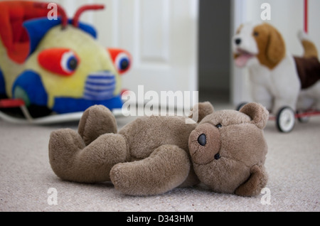 Brown teddy bear laying on a child's bedroom floor. Stock Photo