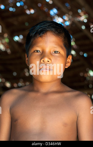 A Yagua young boy inside a maloca (traditional house with thatched roof), surroundings of Iquitos, Amazonian Peru Stock Photo