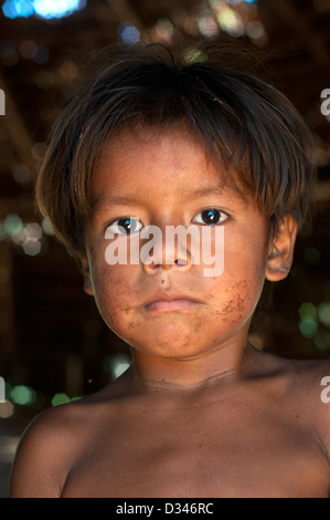 A Yagua young boy inside inside a maloca (traditional house with thatched roof), surroundings of Iquitos Stock Photo