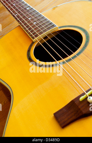 Detail of six stringed acoustic guitar showing part of the neck with fretboard and strings and the hole Stock Photo