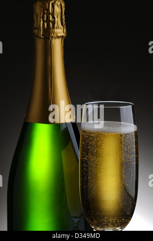 Closeup of a champagne bottle and flute on a light to dark gray background. Stock Photo
