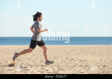 Man running on the beach with the sea in the background Stock Photo