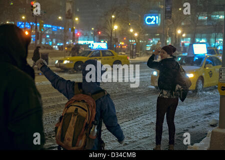 New York, USA. 8th February 2013. A young woman tries to hail a taxi on Columbus Avenue as heavy snow blankets New York City. Credit:  Joseph Reid / Alamy Live News Stock Photo