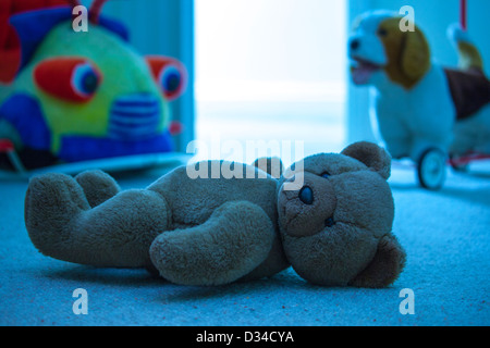 Brown teddy bear laying on a child's bedroom floor. Blue tone. Stock Photo