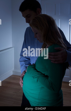 Young pregnant woman and male partner silhouetted at home. Stock Photo