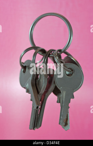 Bunch of steel keys on key ring against pink background Stock Photo