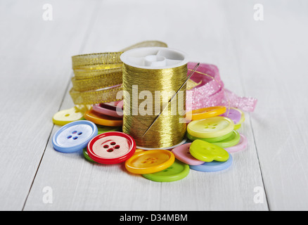 Multi-colored buttons, gold thread and ribbons on a wooden background Stock Photo