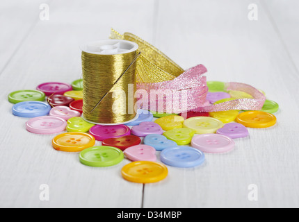 Multi-colored buttons, gold thread and ribbons on a wooden background Stock Photo