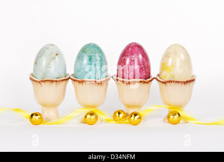 Marble Easter eggs in egg cups with yellow ribbon and gold wrapped chocolate candies Stock Photo