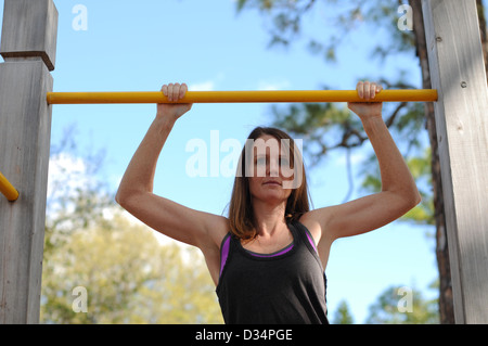 young strong and pretty woman doing pull ups outdoors Stock Photo