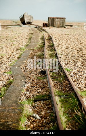 View of rail track leading to old fishing boat and hut at Dungeness in Kent, UK. Stock Photo