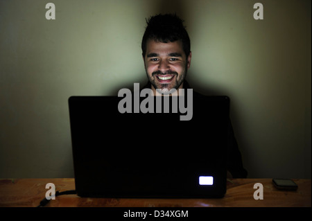 Happy young man on laptop computer smiling Stock Photo