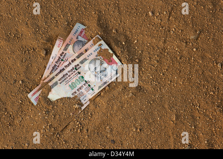 Indian thousand rupee notes on a dirt track. India Stock Photo