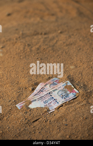 Indian thousand rupee notes on a dirt track. India Stock Photo