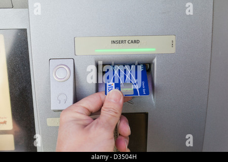 Man inserting debit card into ATM machine Stock Photo