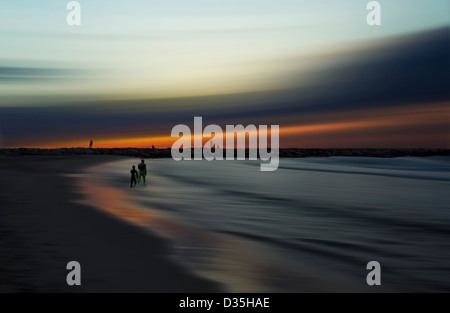 Scenic view with distorted landscape and sky with silhouetted figures walking on beach