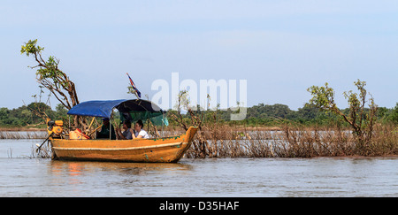 Visitors in small boat wait on Mekong River to see rare fresh water Irrawaddy dolphins. Stock Photo