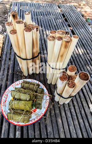 Sweet, sticky rice is combined with red beans and sealed in bamboo tubes that are topped with coconut husks in Cambodia Stock Photo