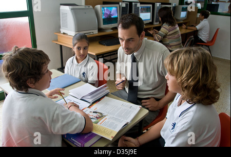 LANGUAGE GROUP TEACHER Small interactive study group of junior school pupils with attentive male teacher in  foreign language lesson Stock Photo