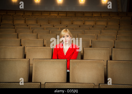 Single woman sitting lonely in an empty cinema or theatre Stock Photo
