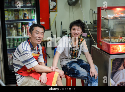 Family business: cheerful shopkeepers sitting in their Chinese dumpling shop Stock Photo