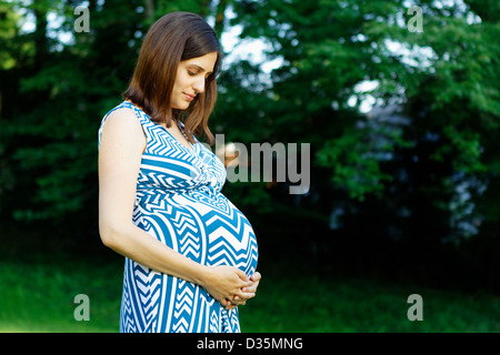 A pregnant young woman looking at her belly Stock Photo