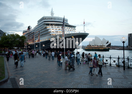 Crowds promenade in front of Cunard's Queen Elizabeth berthed at the overseas passenger terminal Circular Quay Sydney Australia. Stock Photo