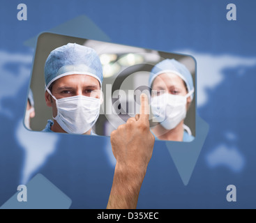 Hand selecting image of surgeons on touchscreen Stock Photo