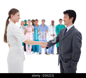 Business people shaking hands with medical staff in background Stock Photo