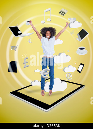 Happy woman jumping on a tablet pc Stock Photo