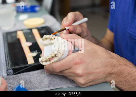 Closeup of a dental technician applying porcelain to a dentition mold in a lab Stock Photo