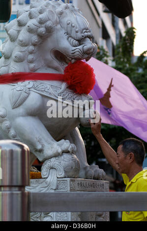 Bangkok, Thailand  11th February 2013.  man prays for a good 'year of the snake' by touching a large stone carved Lion statue at the Chinese new year festival, Bangkok Credit:  Kraig Lieb / Alamy Live News Stock Photo