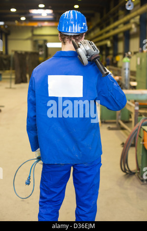 Construction worker with helmet and angle grinder posing in assembly hall Stock Photo