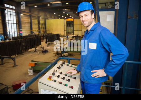Construction worker operating a crane with a control panel Stock Photo