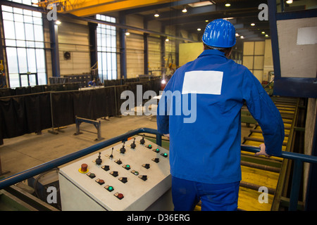 Construction worker operating a crane with a control panel Stock Photo