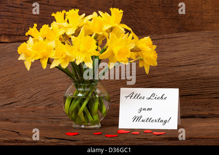 Dear greetings for Mothers Day with a bouquet of daffodils and a white card with the text "Alles Liebe zum Muttertag" Stock Photo