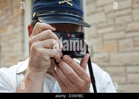 A man wearing a hat takes a photo using his Leica camera. Stock Photo