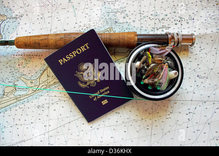 A flyrod and reel rests on a nautical chart with a passport and artificial flies. Stock Photo