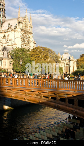 Tourists in dusk sunset sunlight on Pont au Double river Seine Notre Dame Cathedral Paris France Europe Stock Photo