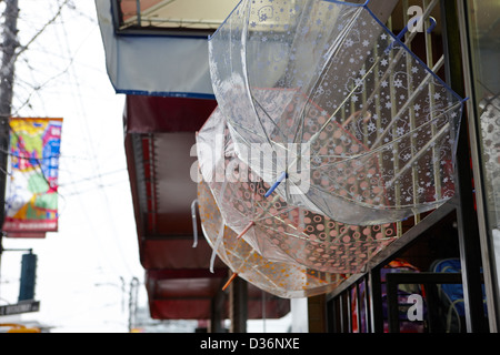transparent umbrellas hanging outside on sale in a shop on a wet rainy day in downtown Vancouver BC Canada Stock Photo