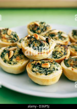Home made bite-sized cheese spinach quiches, stuffed with ricotta, parmesan, spinach, egg, seasoning and nutmeg. Stock Photo