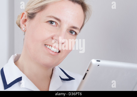 Female medical worker looking at camera holding a digital tablet. Stock Photo