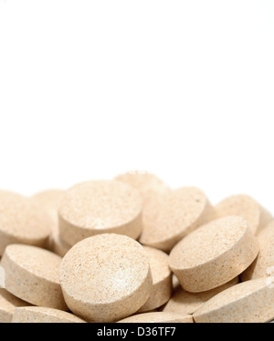 Macro shot of brown tablets on a white background. Stock Photo