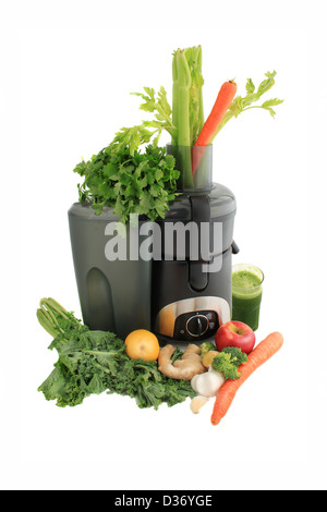 Juicer surrounded by healthy vegetables like carrots, ginger, and kale with fresh made green juice ready to drink Stock Photo