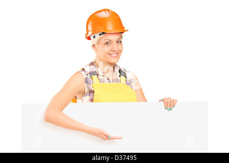 Female manual worker standing behind blank panel and gesturing isolated on white background Stock Photo