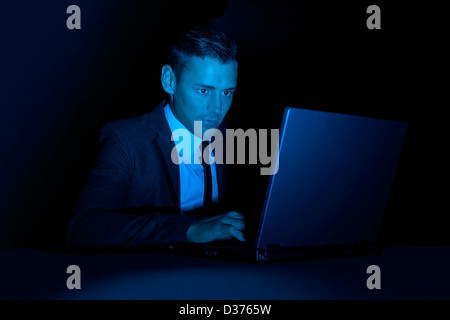 A man working on a laptop computer in the dark Stock Photo