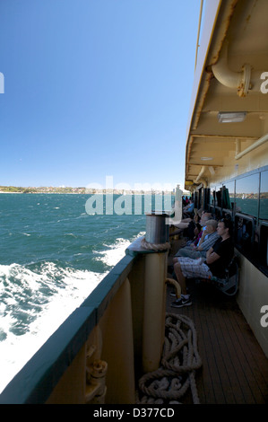 Passengers sitting on the Sydney Ferry as it crosses the Sydney Bay Harbor on a sunny day with blue sky. Stock Photo